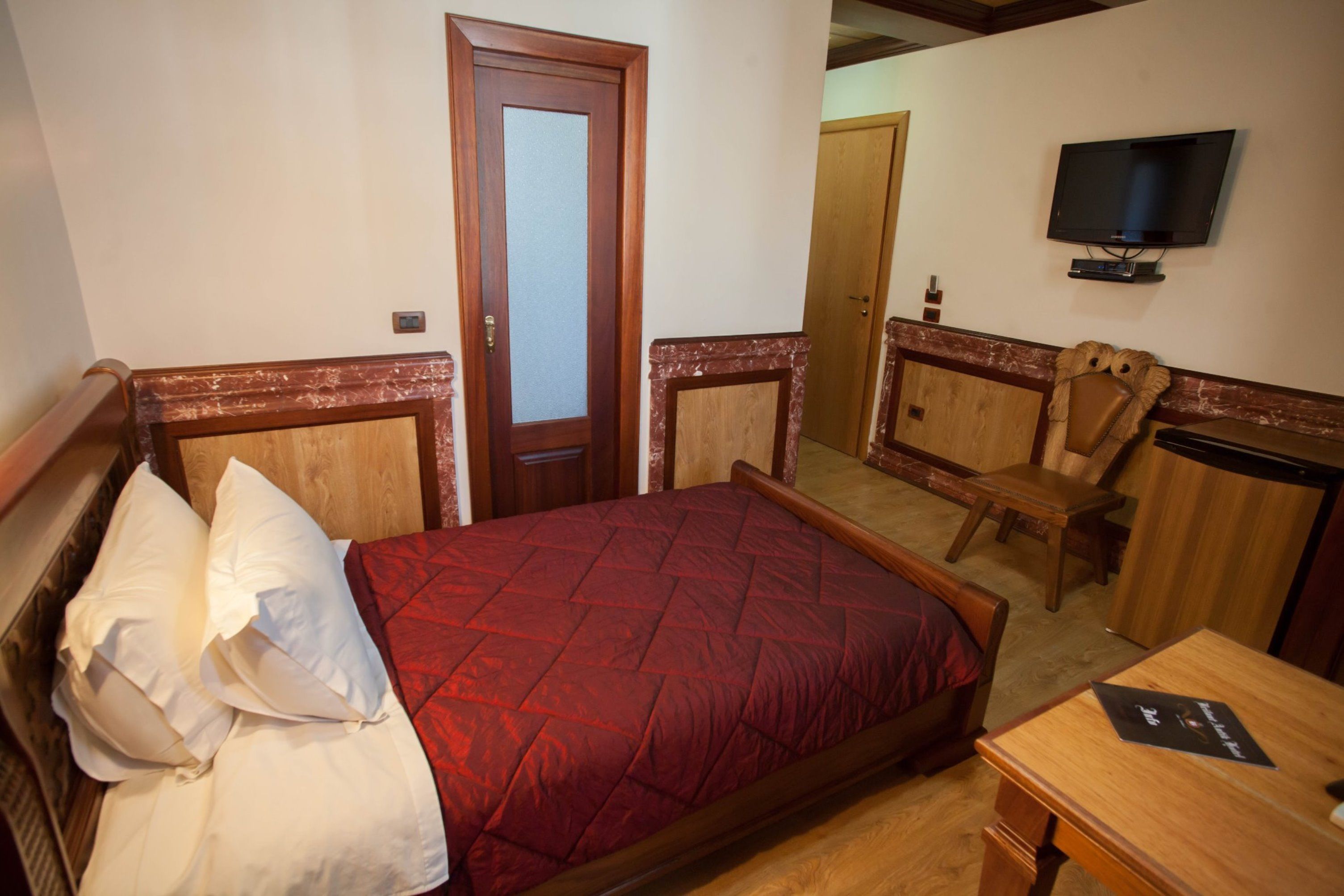 Une chambre d’hôtel comprenant un lit, un bureau, une chaise, une télévision et une armoire.