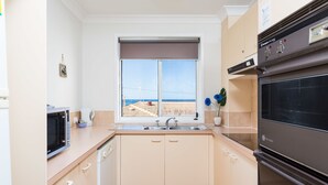 A kitchen with a window, a microwave, a sink, and a stove. - Burleigh Point Holiday Apartments (Miami)