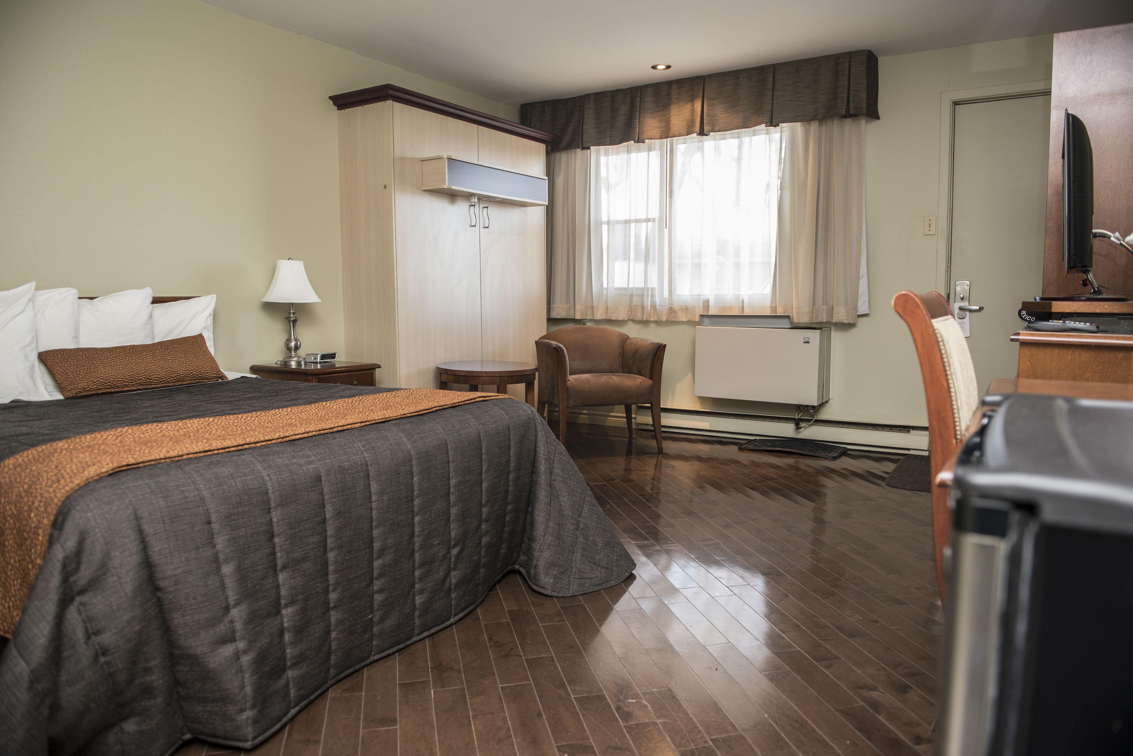 Una habitación de hotel con una cama grande, una silla, un escritorio y una televisión.