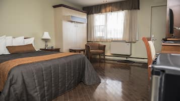 Una habitación de hotel con una cama grande, una silla, un escritorio y una televisión.