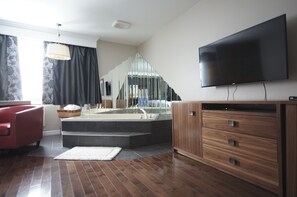 Suite romántica, 1 habitación, para fumadores, hidromasaje | Área de sala de estar | Televisión de pantalla plana de 32 pulgadas con canales por cable 