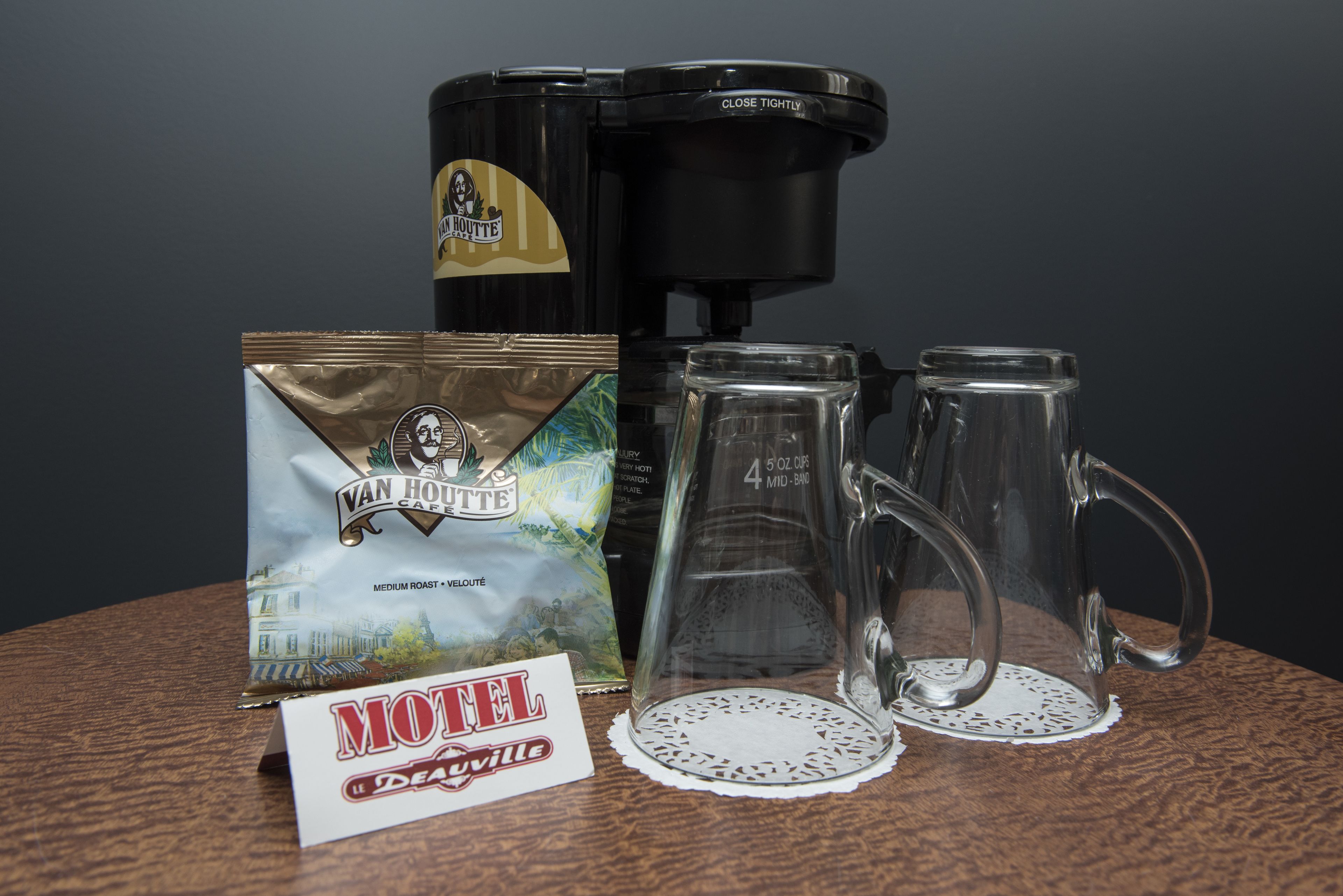 A coffee maker, two glass mugs, a bag of coffee, and a sign reading "Motel de Ayerville".