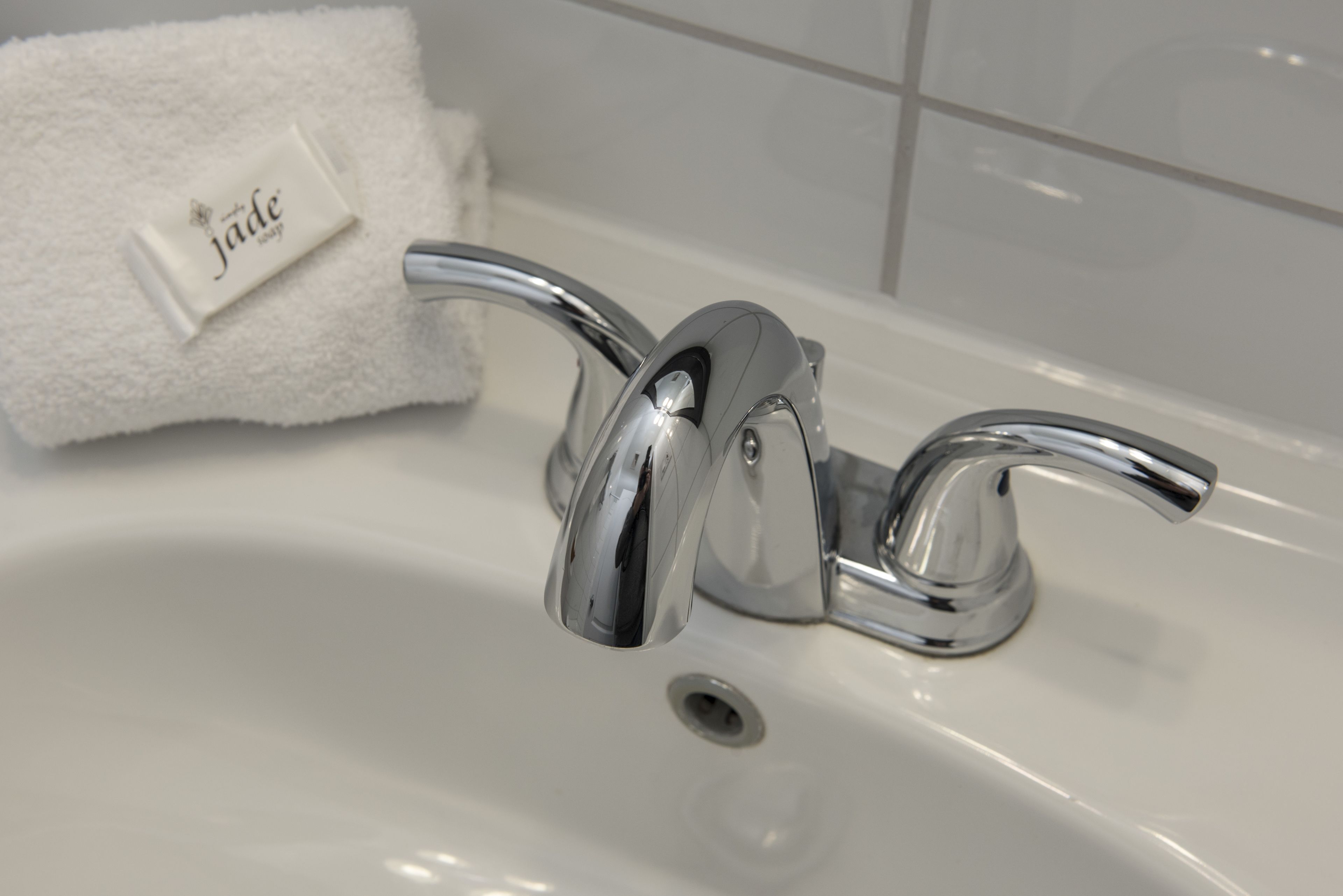 A bathroom sink with a chrome faucet, a white towel, and a soap dish.