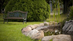 A park with a bench, a pond, and a well-maintained lawn. - Motel Le Deauville (Trois-Rivieres)