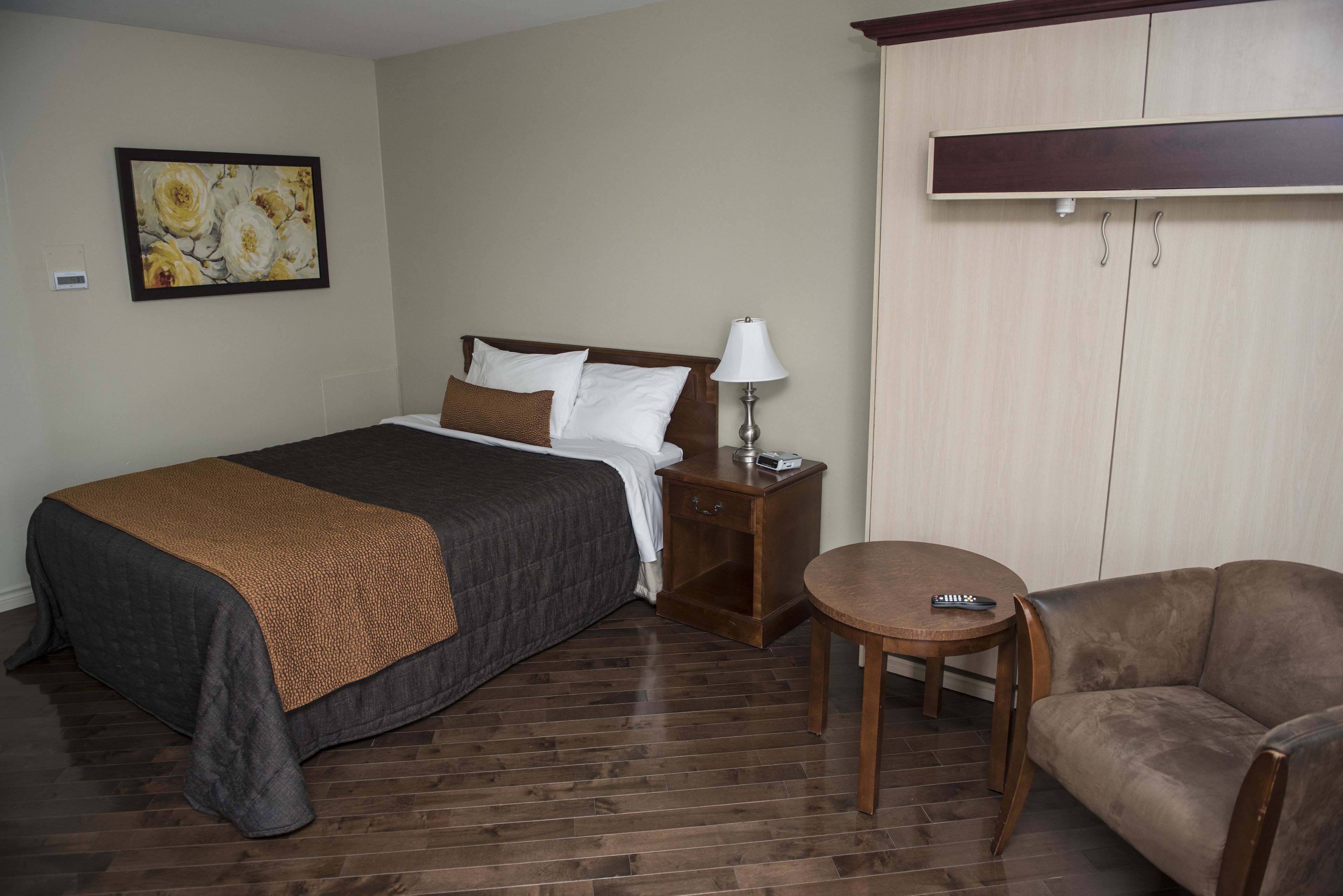 A hotel room with a bed, a nightstand with a lamp, a small round table, and a sofa.