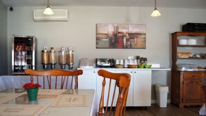 A dining area with a table, chairs, a coffee machine, a toaster, and a refrigerator. - Motel Le Deauville (Trois-Rivieres)