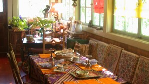 Een eethoek met een lange tafel gedekt voor een maaltijd, omringd door gestoffeerde meubels en houtwerk.