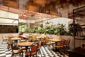 A cafe with checkered flooring, wicker chairs, and tables. - Hotel Harry, an Ascend Collection Hotel (Surry Hills)