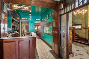 A reception area with a sign, a counter, and a staircase leading to a balcony. - Hotel Harry, an Ascend Collection Hotel (Surry Hills)
