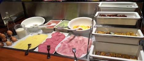 Ein Buffet mit verschiedenen Speisen, darunter Fleisch, Käse und Obst.