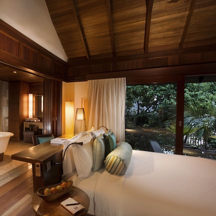 A spacious bathroom with a bathtub, vanity, and large windows overlooking a garden.