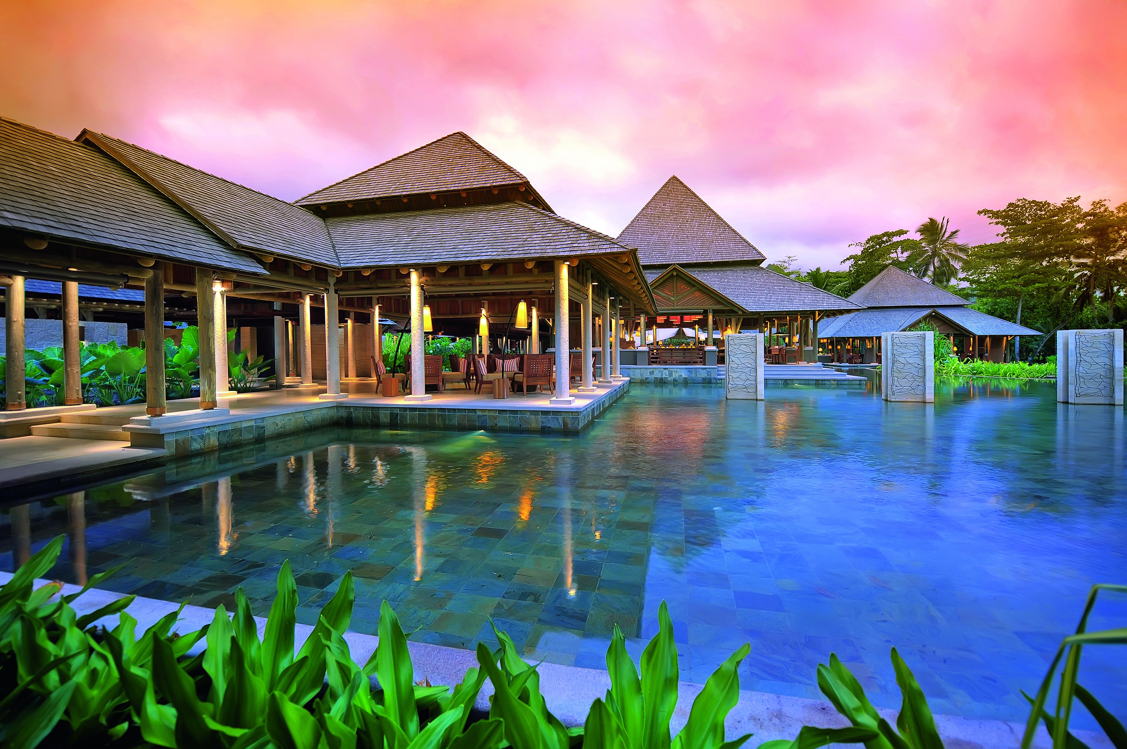 Un resort con múltiples bungalows sobre el agua, una piscina central y abundante vegetación.