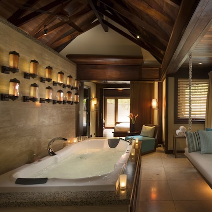 A spa room with a large bathtub, a sofa, and a wall of wall-mounted lights.
