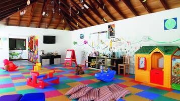 Een speelruimte met kleurrijk foam, een poppenhuis en verschillende speelgoed.