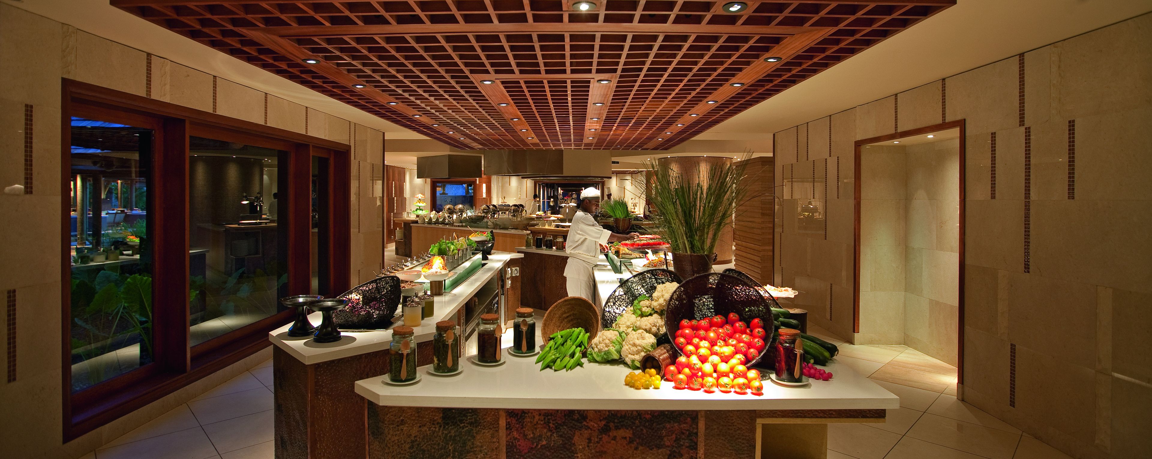 A well-lit kitchen area with a variety of fresh produce displayed on a counter, including tomatoes, cauliflower, and green beans.