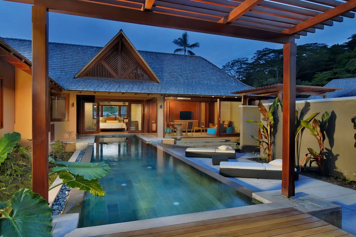 Un resort moderno con piscina, terraza de madera y un área de estar exterior techada.