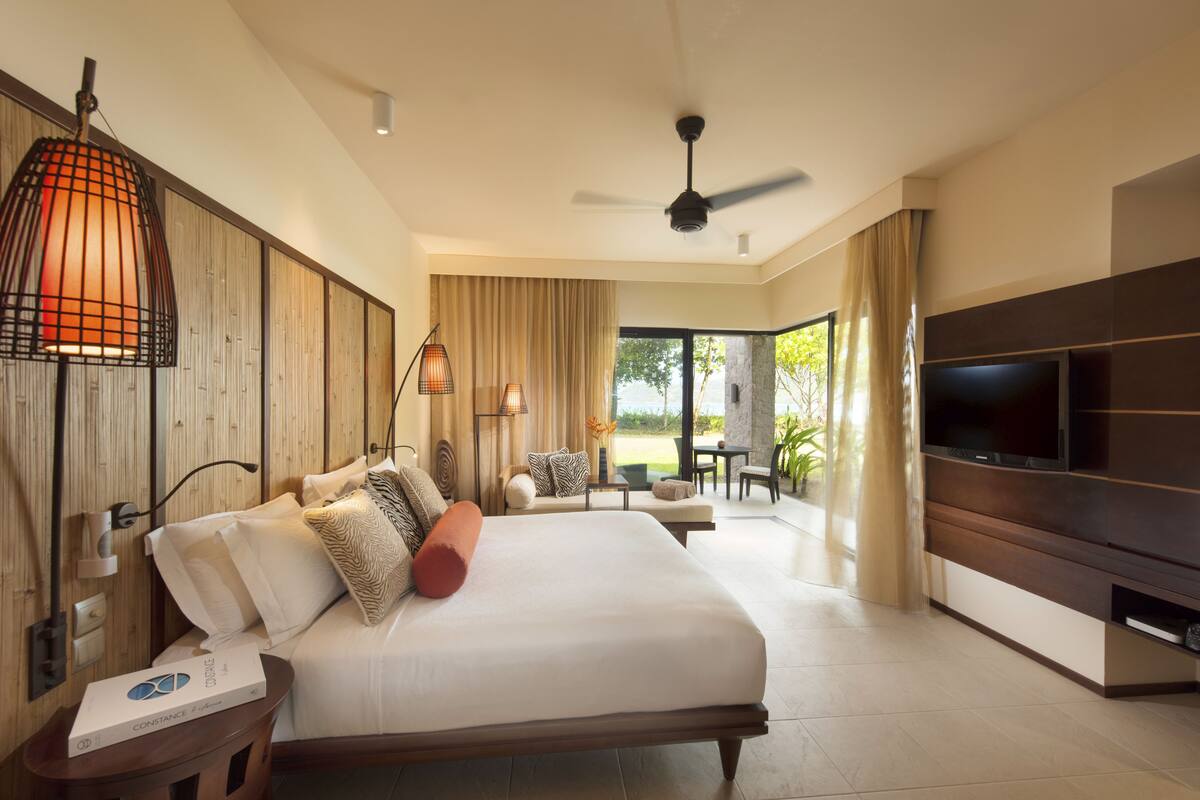 Habitación de hotel con una cama grande, televisor de pantalla plana, ventilador de techo y vistas al exterior.