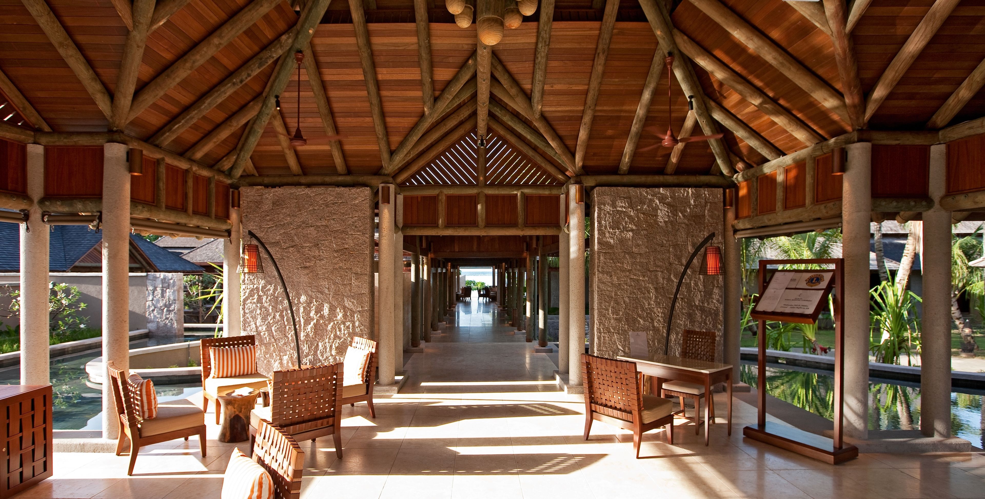 A covered outdoor area with wooden furniture and a stone wall.