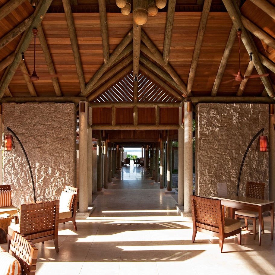 A covered outdoor area with wooden furniture and a stone wall.