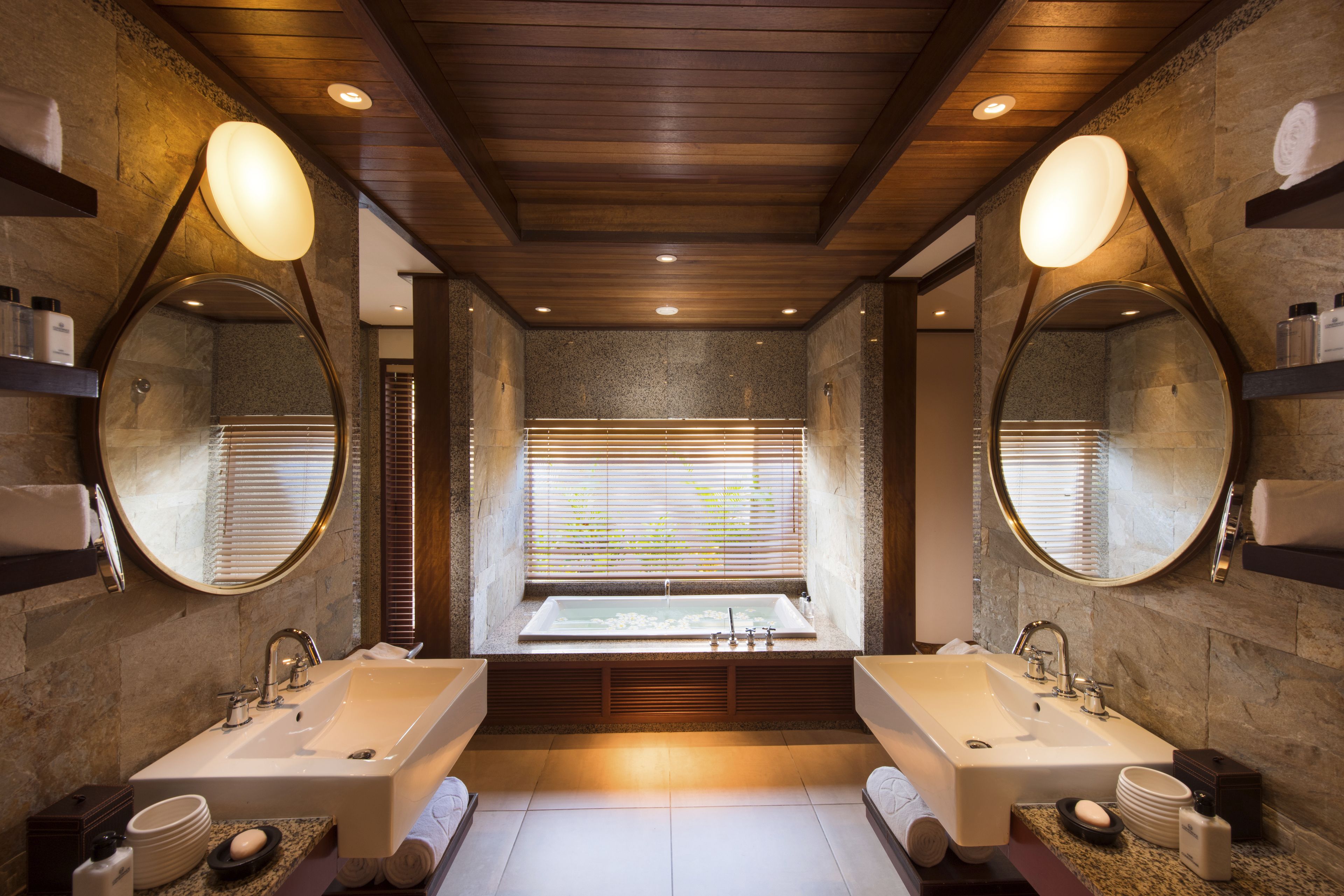Une salle de bain moderne avec deux lavabos, une grande baignoire et une fenêtre équipée de stores.