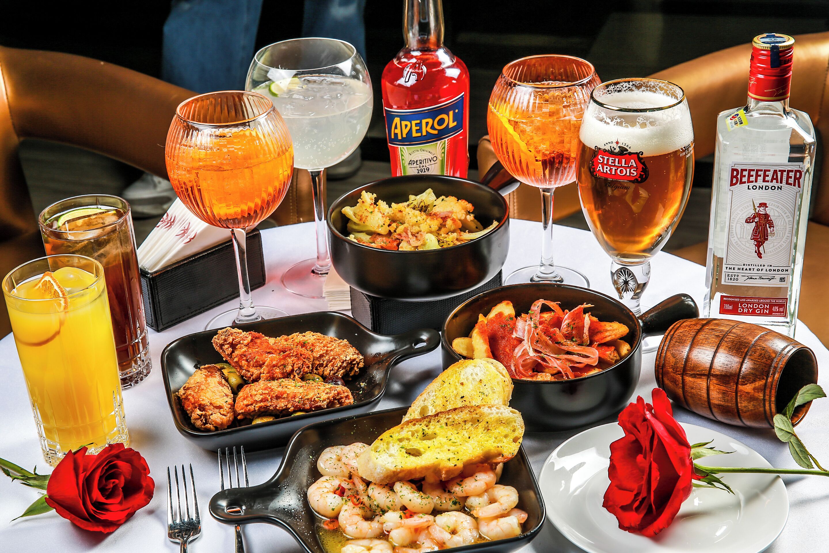 A table with various dishes, drinks, and a rose.