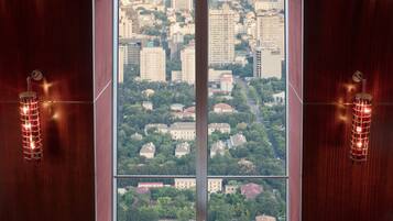 A dining area with a table set for two, a city view through large windows, and a patterned floor.