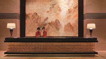 A reception area with a large mural of mountains, two receptionists, and a modern reception desk.
