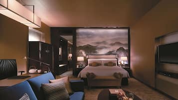 A hotel room with a large bed, a sofa, a coffee table, and a TV.