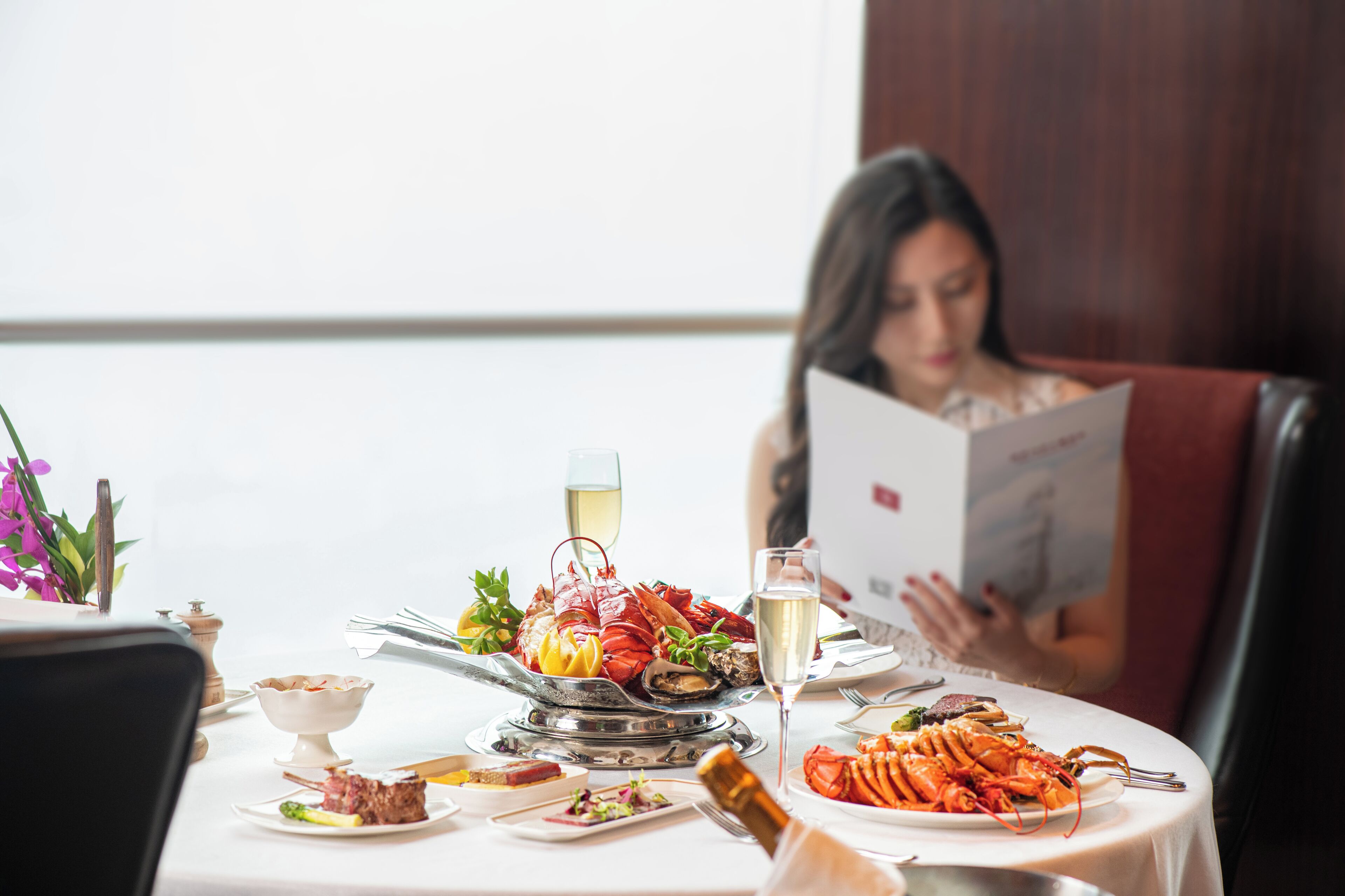 A dining table with seafood, a bottle of champagne, and a menu.