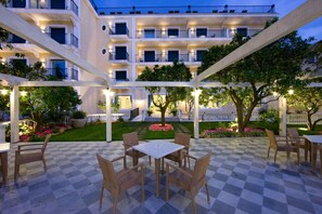 A courtyard with checkered flooring, outdoor seating, and a multi-story building with balconies. - Grand Hotel La Favorita (Sorrento)