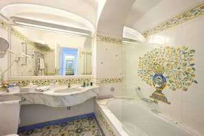 A bathroom with a marble sink, a bathtub, and a shower with a glass door.