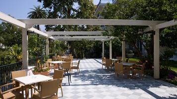 An outdoor patio with checkered flooring, wicker furniture, and a pergola structure.