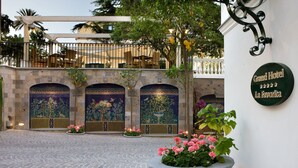 Un pati amb un paviment de rajoles, parets decoratives i un cartell de Grand Hotel La Favorita.