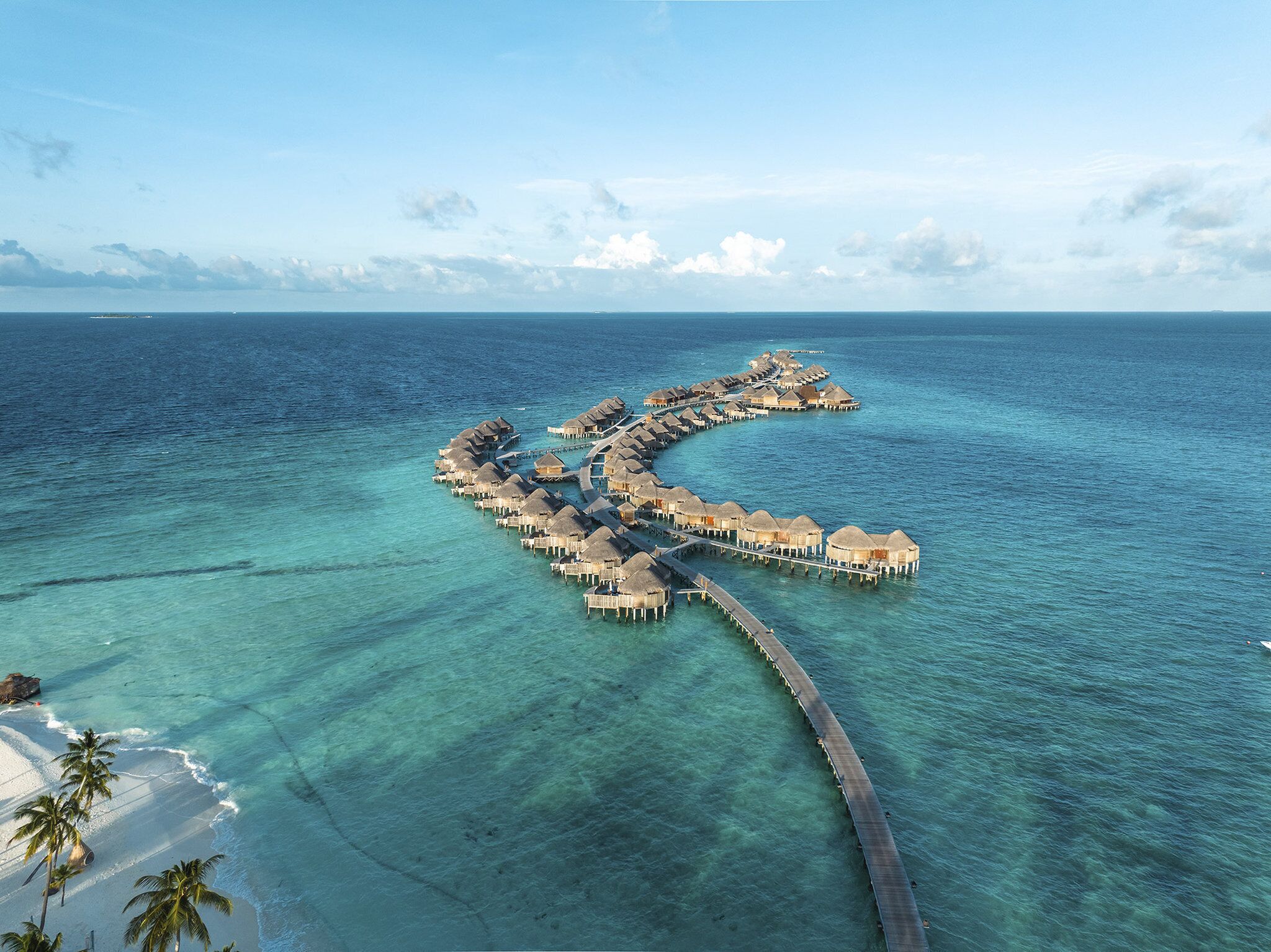 An overwater resort with thatched-roof bungalows connected by walkways.