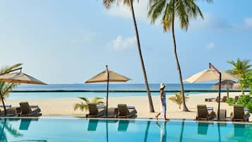 Una piscina al aire libre, sombrillas, sillones reclinables de piscina