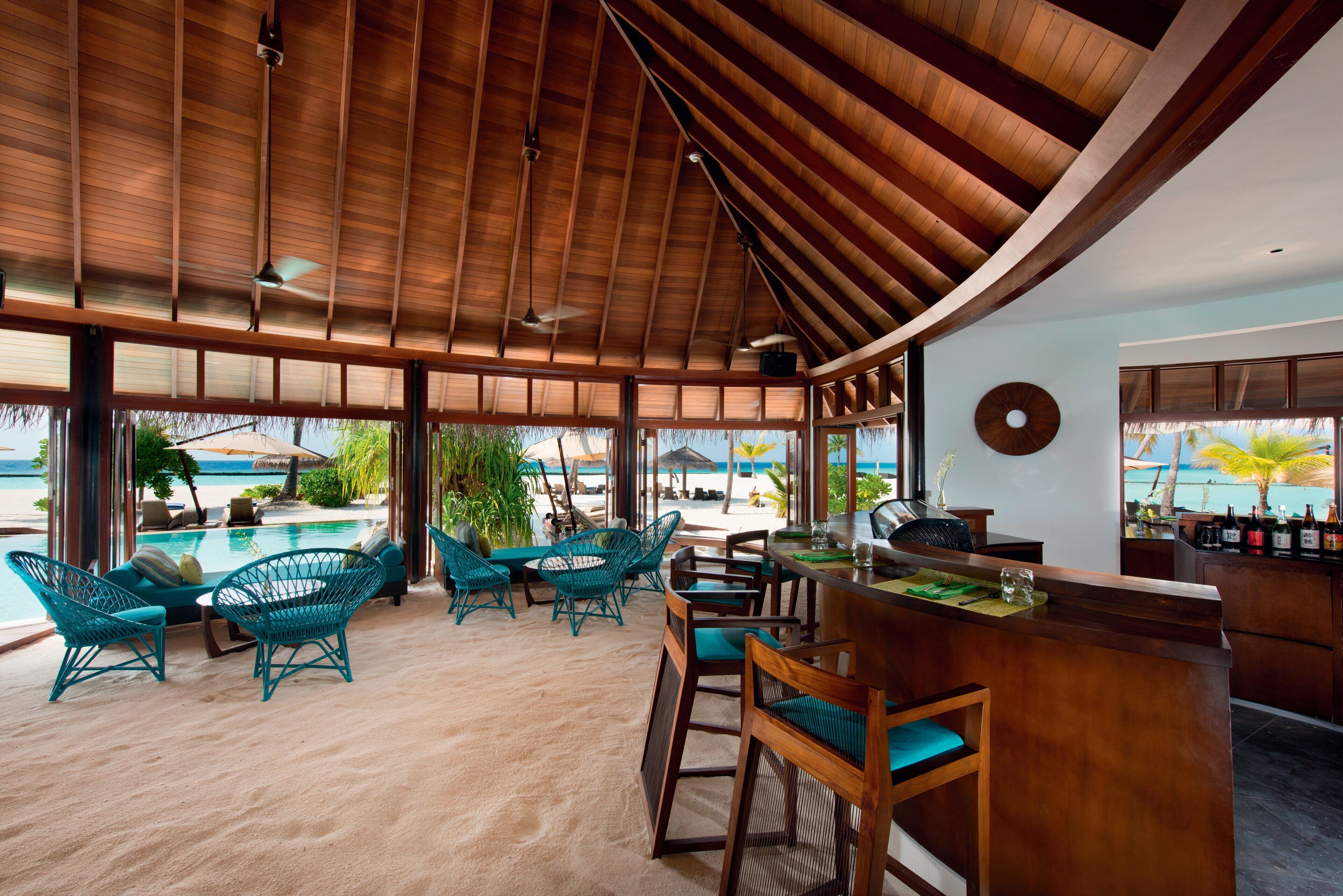 Un bar en la playa con muebles de madera y vista al océano.