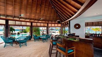 Un bar en la playa con muebles de madera y vista al océano.