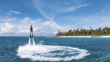 Uma pessoa praticando jet ski em um dia claro, com uma ilha tropical ao fundo.