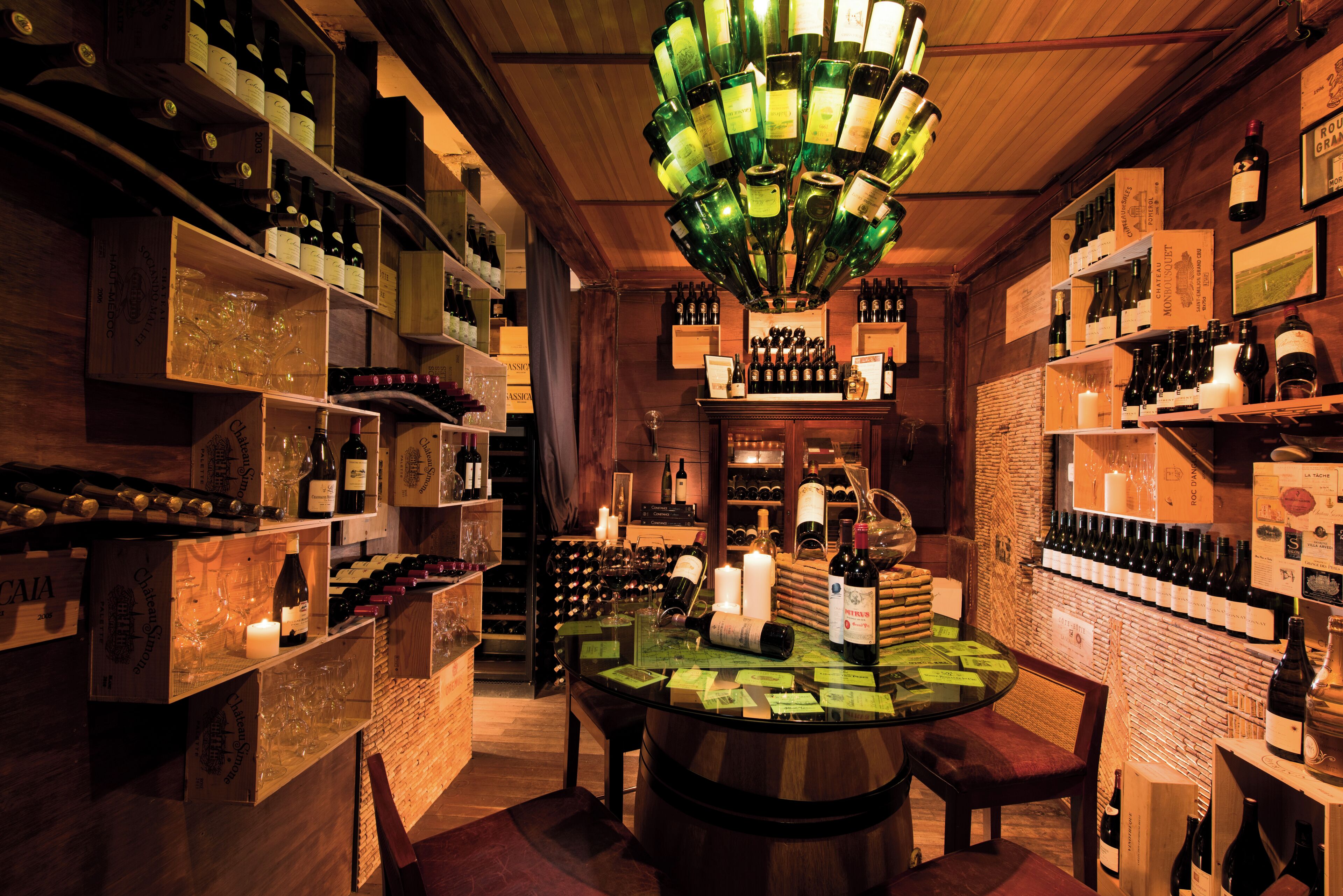 Una cava de vinos con estantes de madera, una mesa central y diversas botellas de vino.