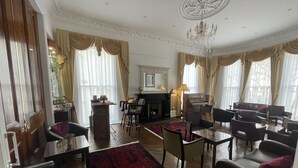 Un salon spacieux avec un piano, des sièges confortables, une cheminée et de grandes fenêtres avec des rideaux.