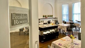 Une salle de petit-déjeuner avec un buffet, des tables, des chaises et un panneau indiquant la fonction de la pièce.