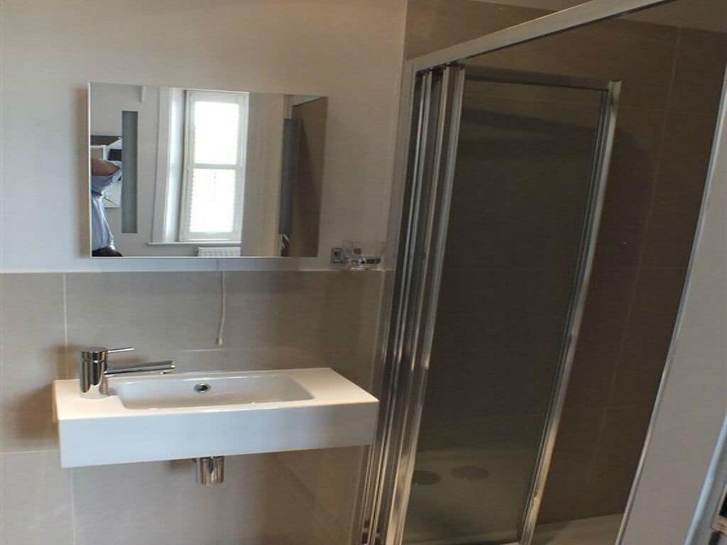 A bathroom with a white sink, a mirror, and a glass shower enclosure.