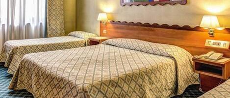 Une chambre d’hôtel avec deux lits, chacun recouvert d’une couvre-lit à motifs et doté d’une table de chevet avec une lampe.