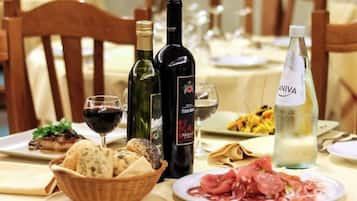 Una mesa de comedor con platos de comida, botellas de vino y copas.