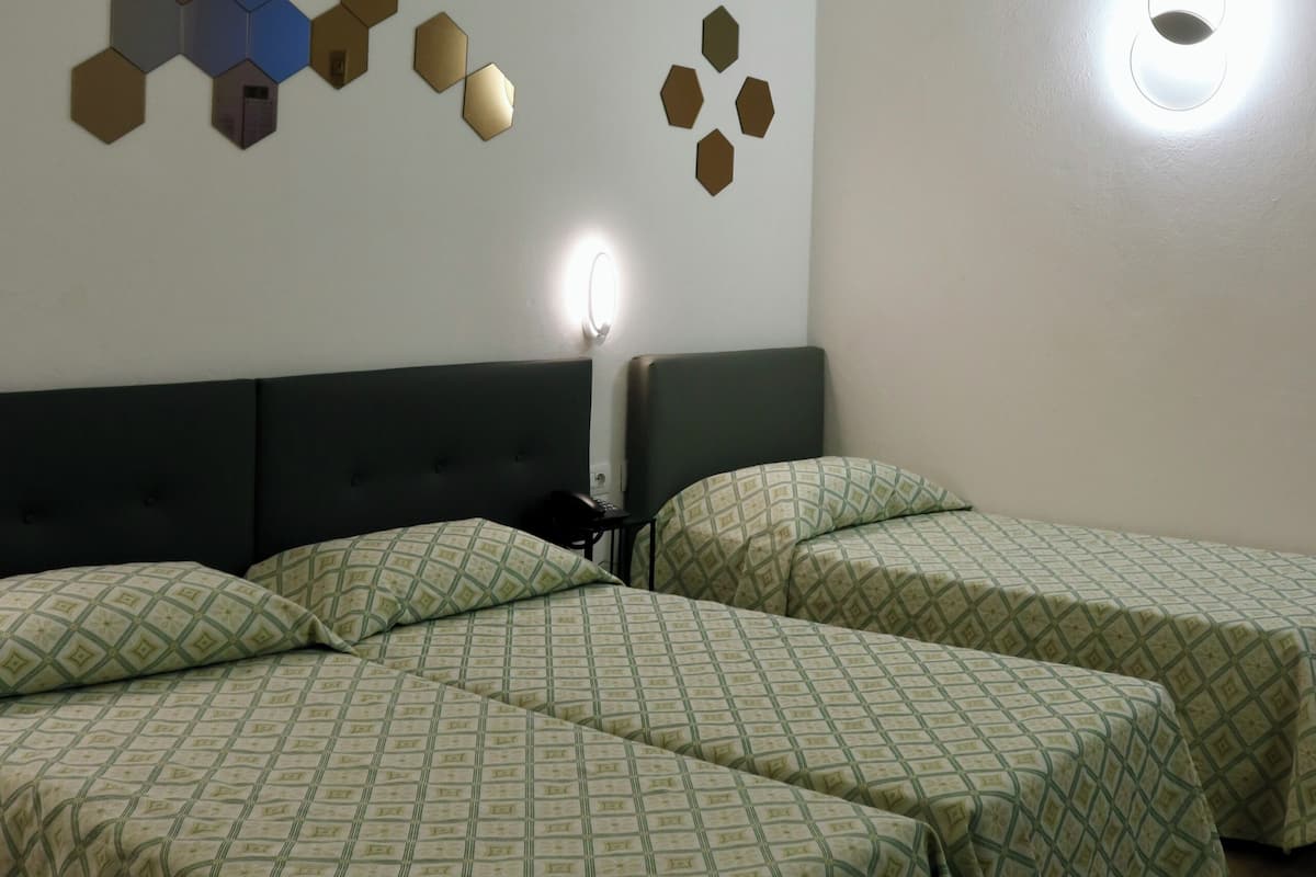 Ein Hotelzimmer mit zwei Betten, einem Kopfteil, einer Wandleuchte und einer geometrischen Wanddekoration.