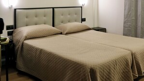 A hotel room with a large bed, two bedside tables, a nightstand, and a wall-mounted light fixture.