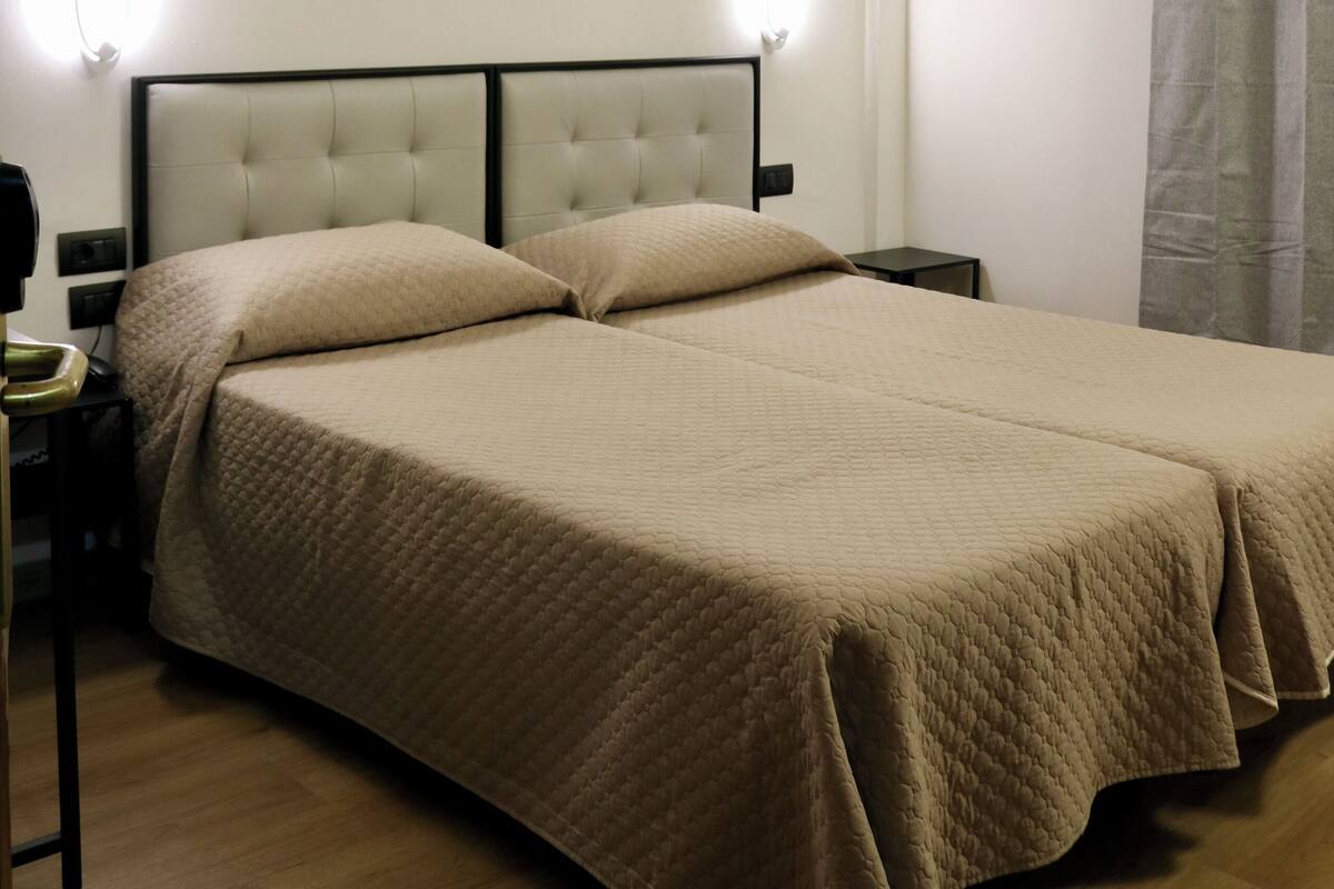 Ein Hotelzimmer mit einem großen Bett, zwei Nachttischen, einer Ablage und einer wandmontierten Lampe.