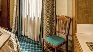 A room with a wooden chair, a table, and patterned curtains.