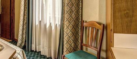 A room with a wooden chair, a table, and patterned curtains.