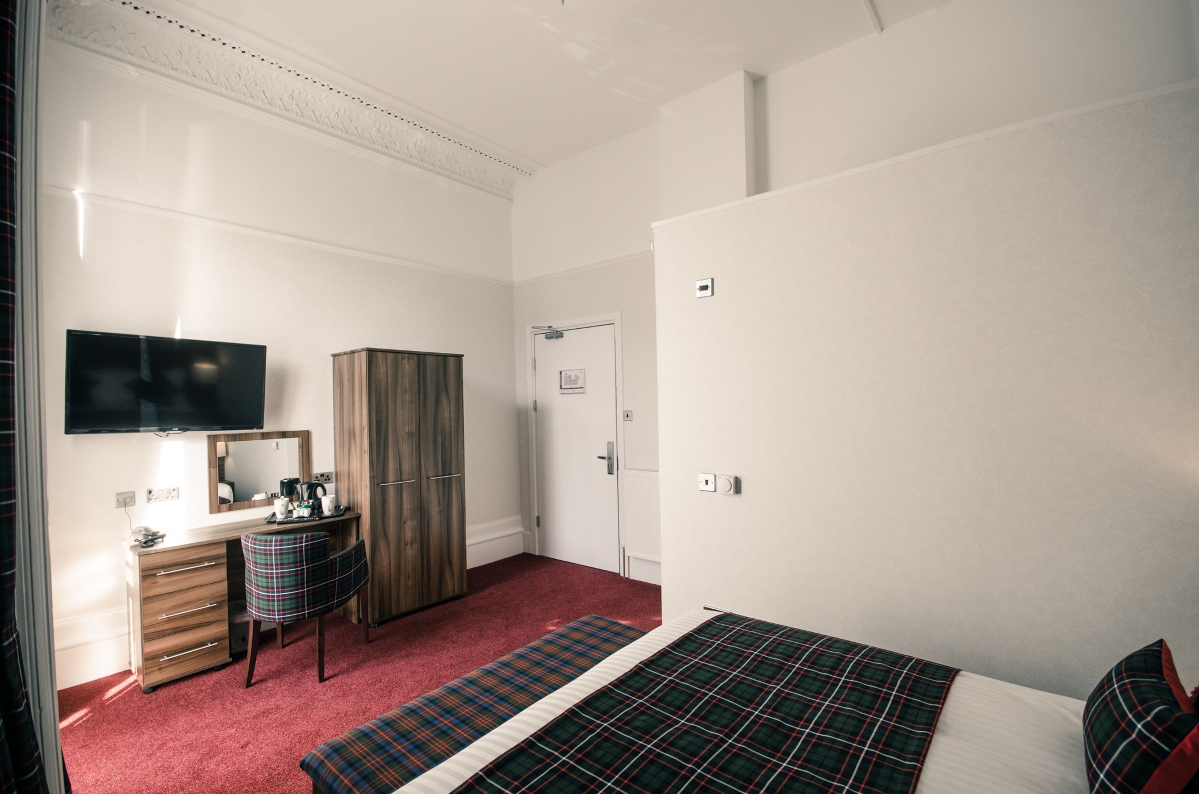 Ein Schlafzimmer mit einem Bett, einem Schreibtisch, einem Stuhl, einem Kleiderschrank und einem Fernseher.